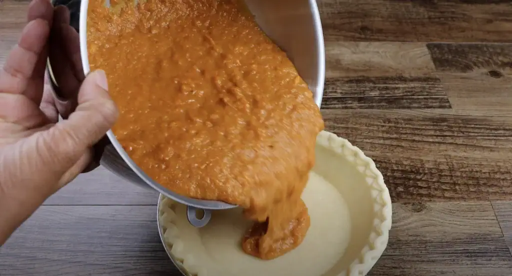 Filling the pie shell for sweet potato pie