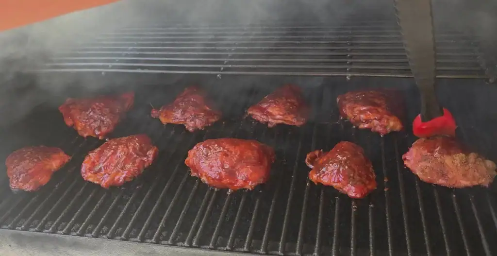 Adding BBQ sauce to smoked chicken thighs