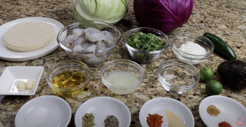 Ingredients laid out for shrimp tacos — shrimp, avocado, cilantro, cabbage, limes, garlic, and spices for bold flavor