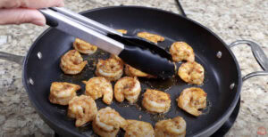 Cooking seasoned shrimp in a skillet until golden and juicy for delicious homemade shrimp tacos.