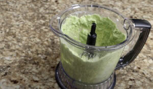 Blending avocado, cilantro, lime juice, and sour cream to make a creamy taco sauce for shrimp tacos.
