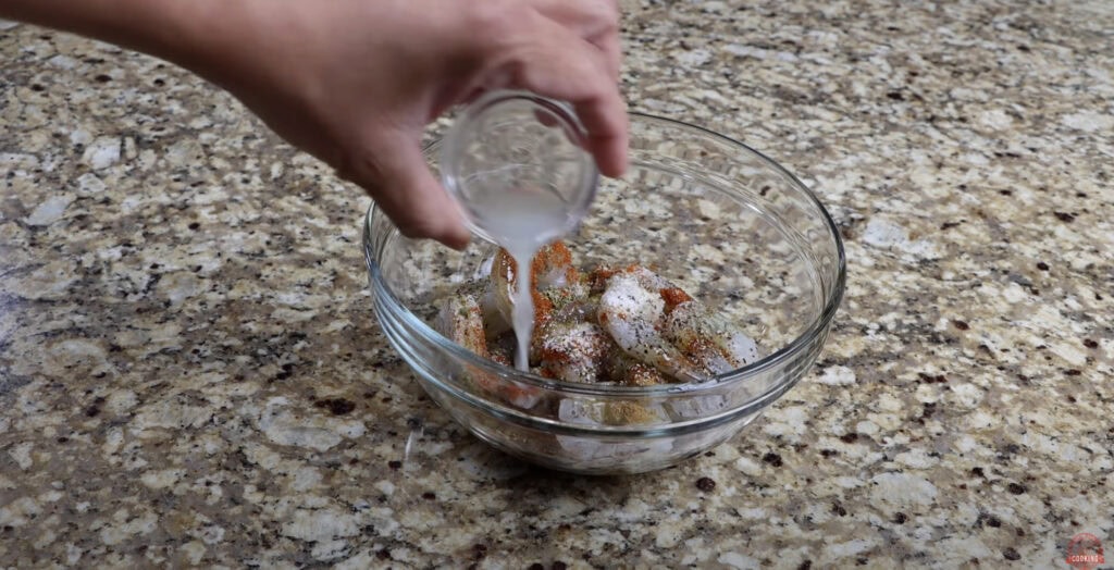 Seasoning raw shrimp with lime juice, paprika, garlic powder, and black pepper for flavorful shrimp tacos.