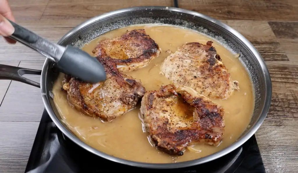 Returning pork chops to gravy to simmer