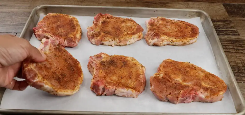 Placing Pork Chops on Baking Sheet lined with Parchment Paper