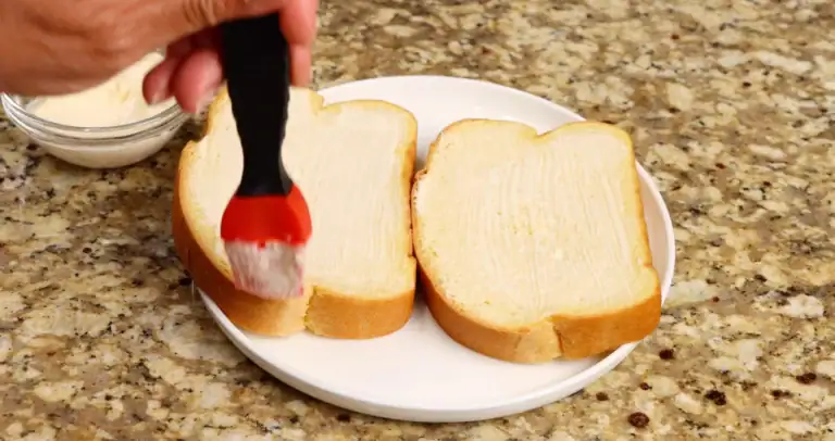 Brushing mayo on bread for breakfast sandwich