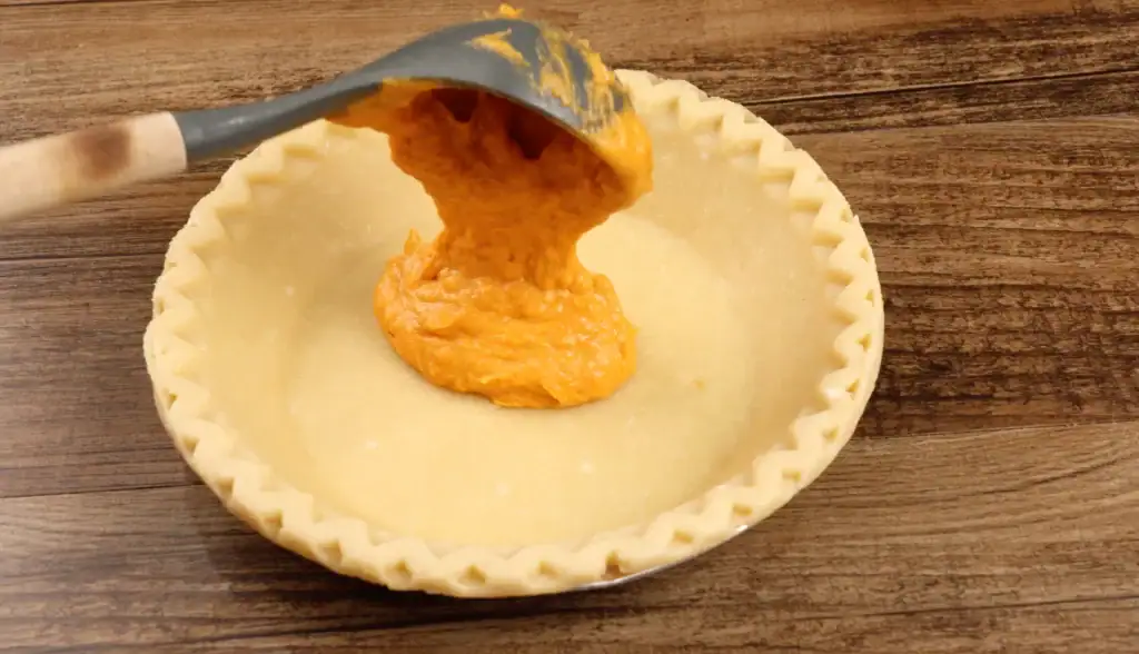 Adding the pie filling to pie crust for Brown Butter Sweet Potato Pie