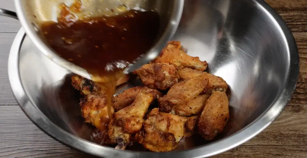 Pouring Peach Sauce over Wings
