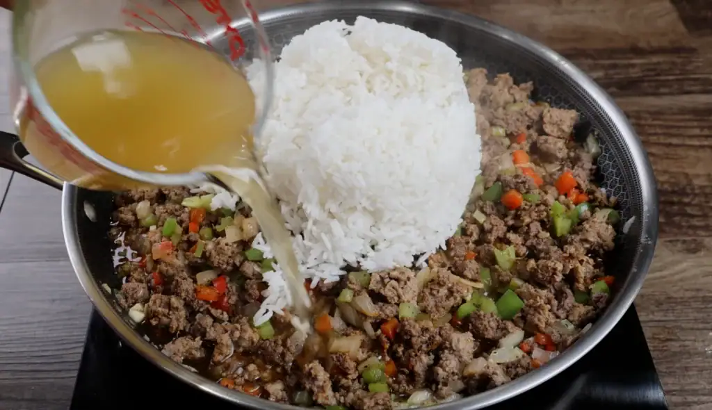 Adding the Rice and Chicken Broth to the pan for Shrimp Dirty Rice