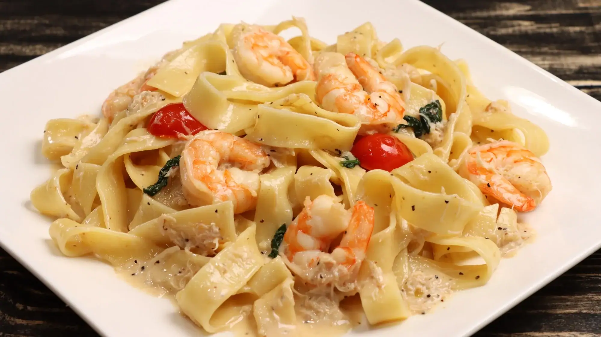 Seafood Pasta with cherry tomatoes and spinach on a white plate