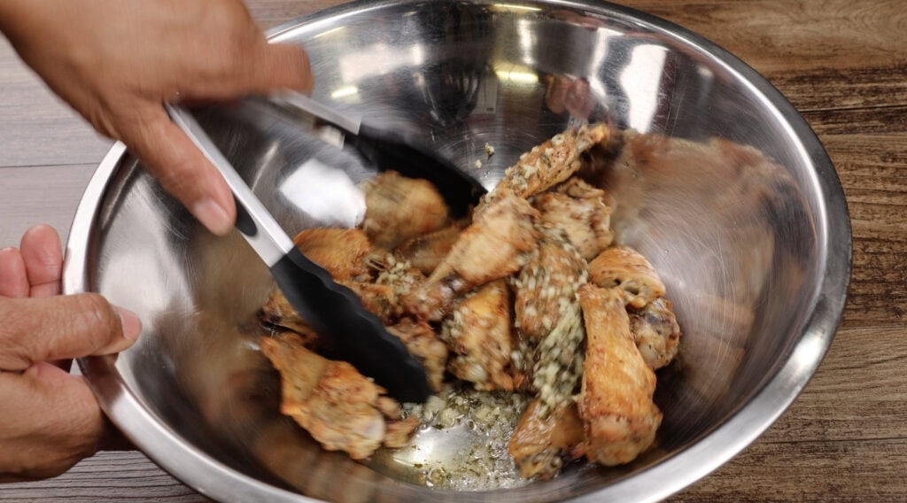 Coating the wings with the butter garlic sauce