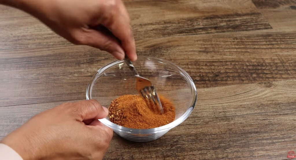 Dry rub seasoning being stirred with a fork in a small glass bowl for Ghost Pepper Wings