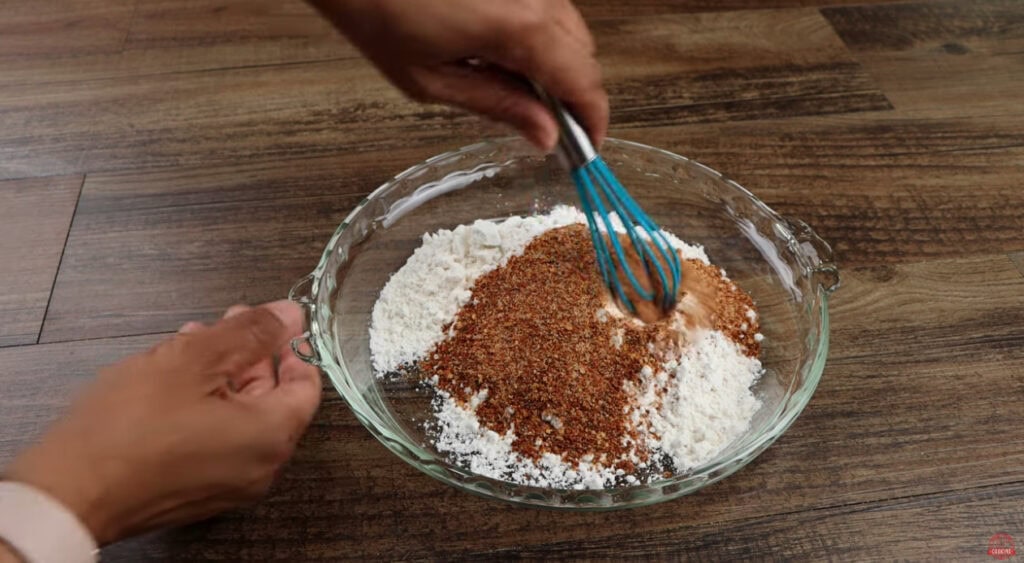 Flour and ghost pepper seasoning being whisked together in a glass bowl for the Ghost Pepper Wings coating
