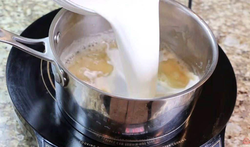 Half-and-half being poured into the butter and flour mixture to make the creamy soup base.