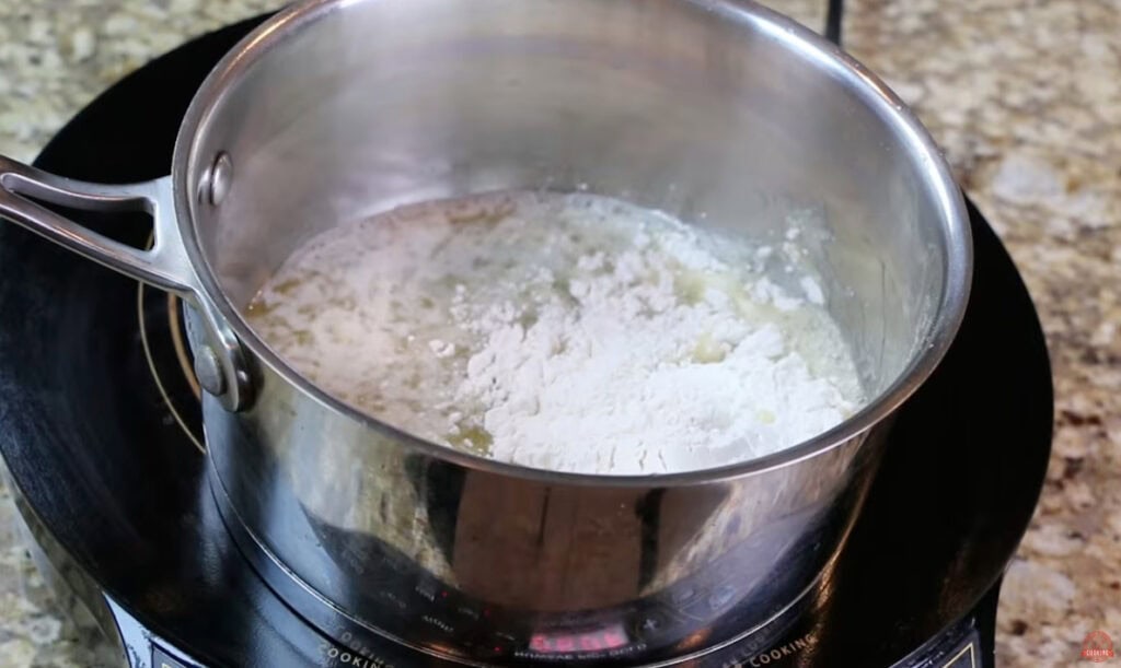 Flour added to melted butter in a saucepan to make a roux for ham and potato soup.