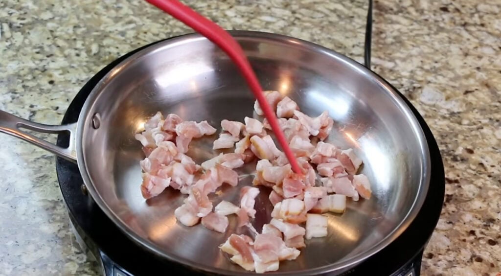 Chopped bacon cooking in a stainless steel skillet for the ham and potato soup topping.