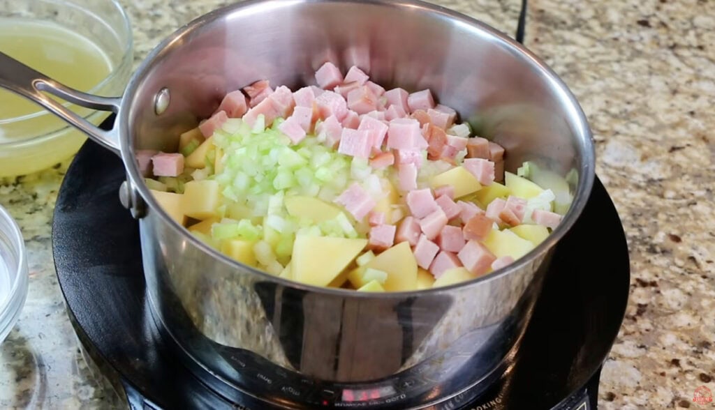 Diced potatoes, ham, celery, and onion in a pot before adding the soup broth.